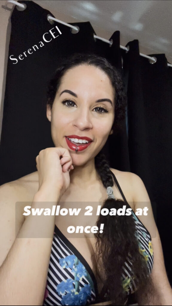 Serena's bright red lipstick makes her smile pop! She is sitting in front of black curtains in a sports bra with flowers printed on top of black and white stripes. The title states "Swallow 2 loads at once!"